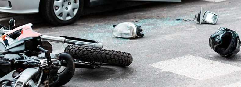 Motocicleta volcada y casco en la carretera después de una colisión con un automóvil