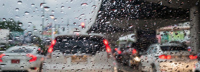 Tráfico en día lluvioso con vista de la carretera a través de la ventanilla del coche con gotas de lluvia